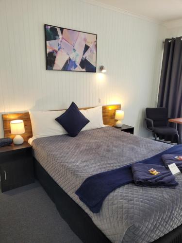 a bedroom with a large bed with blue pillows at Glynlea Motel in Horsham
