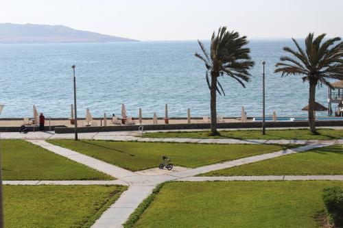 a walkway next to the ocean with palm trees at Departamento con Vista al Mar- Condominio Nautico Las Velas in Paracas