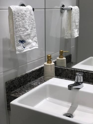 a bathroom with a sink and a mirror and towels at Apartamento em Guarajuba, BAHIA 1 Tudo Novinho e Finamente Decorado in Camacari
