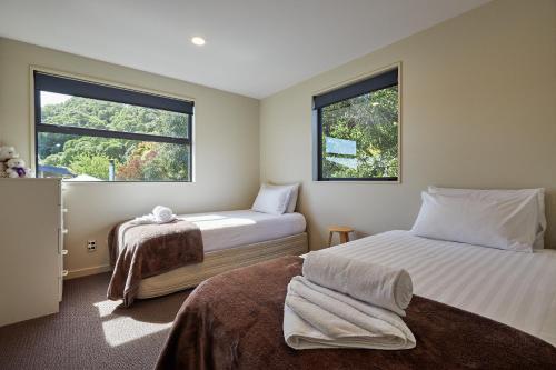 two beds in a room with two windows at Bliss on the Bay in Kaikoura