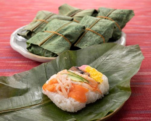 a piece of sushi sitting on a green leaf at Tabist Kanko Business Hotel Matsuyama Hida Takayama in Takayama
