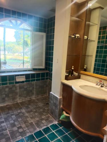 a bathroom with a tub and a sink and a window at Palm Springs Hotel in Chiang Mai