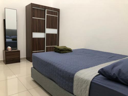 a bedroom with a blue bed and a wooden cabinet at CasaStayz Kluang in Kluang
