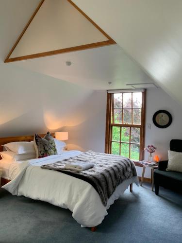 een slaapkamer met een groot bed en een raam bij Quail Farm, Colonial charm in Nelson