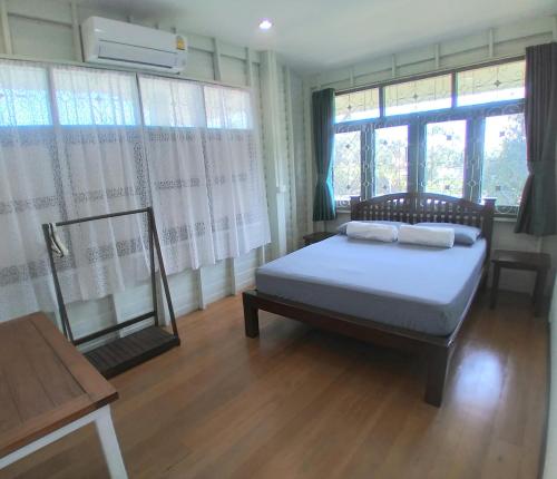 a bedroom with a bed in a room with windows at Green Home by Canal in Ban Tha Long Hip