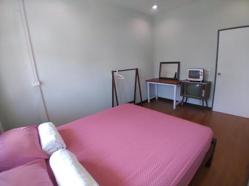 a bedroom with a pink bed and a desk at Green Home by Canal in Ban Tha Long Hip