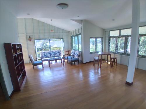 a living room with a table and chairs and windows at Green Home by Canal in Ban Tha Long Hip
