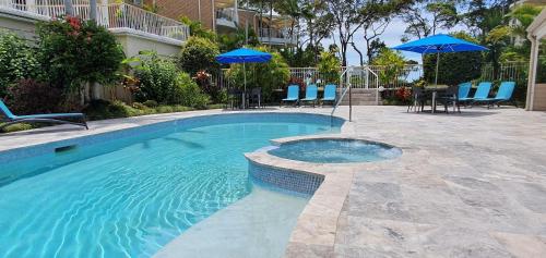 a swimming pool with blue umbrellas and chairs at Serenity Apartments Noosa in Noosa Heads