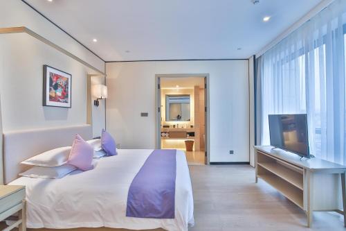 a bedroom with a bed and a desk and a television at SSAW Boutique Hotel Wenzhou Jiushan Lake in Wenzhou