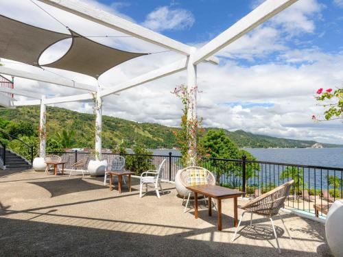 a patio with chairs and tables and a view of the water at Granada Beach Resort - Adults Only in Boljoon