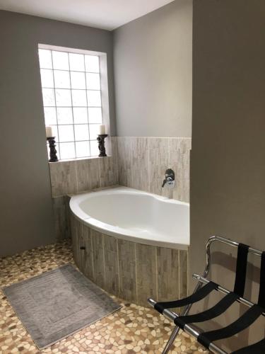 a bath tub in a bathroom with a window at Rueby’s Guesthouse in Dullstroom