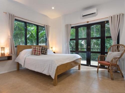 a bedroom with a bed and two chairs and windows at Granada Beach Resort - Adults Only in Boljoon