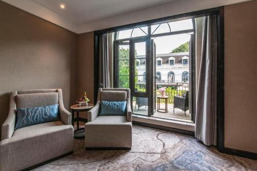 a living room with two chairs and a large window at SSAW Boutique Hotel Lishui Jiarui in Lishui