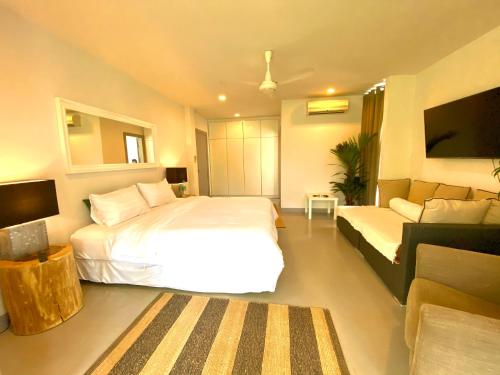 a bedroom with a large white bed and a couch at Natural Villas -Front Samet Beach house with Pool in Rayong