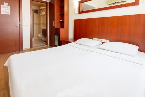 a bedroom with a white bed and a bathroom at Hotel Pelit in Canakkale