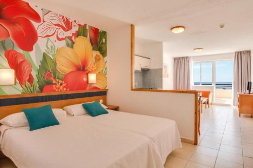 a bedroom with a bed with a painting on the wall at Palm Garden with sea views to the pools and beach in Morro del Jable