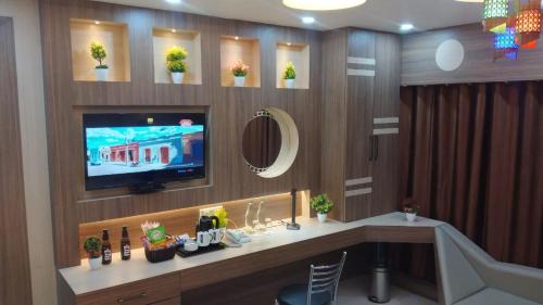 a living room with a tv and a desk with a television at HOTEL CENTRAL SQUARE "A Couple Friendly Hotel" in Muzaffarpur