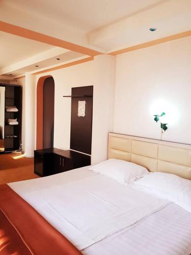 a bedroom with a large white bed and a desk at Asia Hotel in Târgu Jiu
