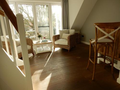 a living room with a chair and a window at Hotel Leegerpark in Greetsiel