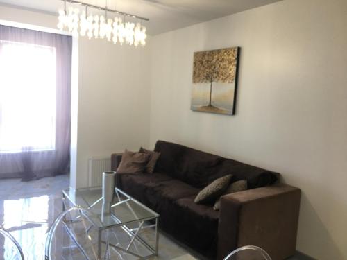 a living room with a brown couch and a glass table at 4-room jacuzzi apartment in Lviv
