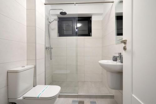 a white bathroom with a toilet and a sink at SIF Residence in Craiova