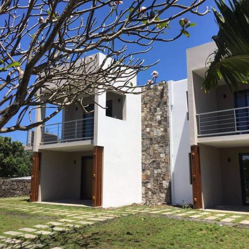 a white building with a palm tree in front of it at Valmarin Seafront Apartments in Trou dʼ Eau Douce