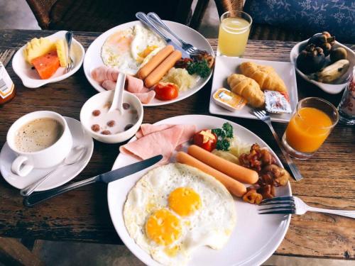 a table topped with plates of breakfast foods and drinks at Lijiang Sunshine Nali Inn in Lijiang