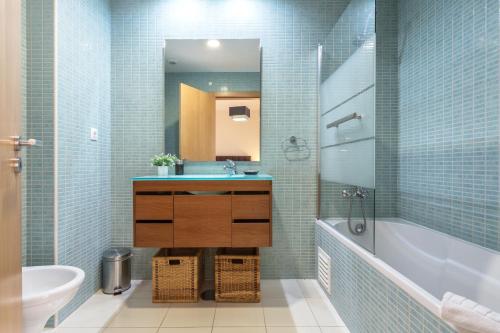 a bathroom with a sink and a tub and a mirror at Privilege Apartment Wanseta with Rooftop Pool, Village Marina - Olhão in Olhão