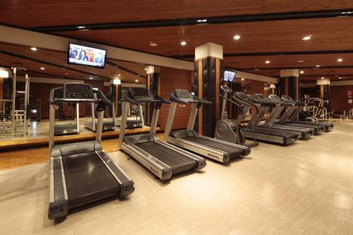 a gym with a row of treadmills and a television at Grand Walkerhill Seoul in Seoul