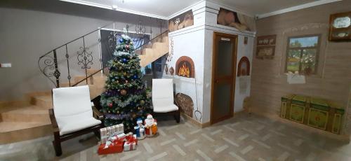 een kerstboom in een woonkamer met een open haard bij Hotel Vdohnovenie in Klin