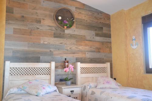 a bedroom with two beds and a wooden wall at Casa Rural & SPA Mirador Gredos in Guijo de Ávila