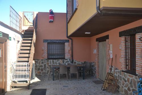 a patio with a table and chairs next to a building at Casa Rural & SPA Mirador Gredos in Guijo de Ávila