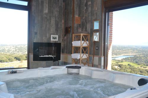 a large bath tub in a room with a fireplace at Casa Rural & SPA Mirador Gredos in Guijo de Ávila
