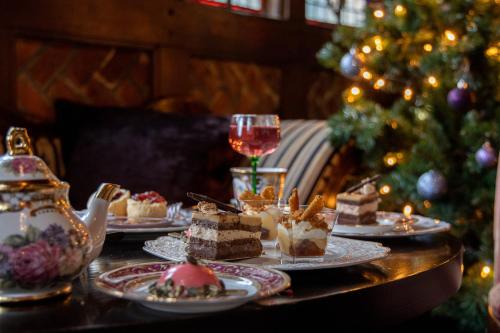 a table topped with plates of desserts and a christmas tree at Langshott Manor - Luxury Hotel Gatwick in Horley