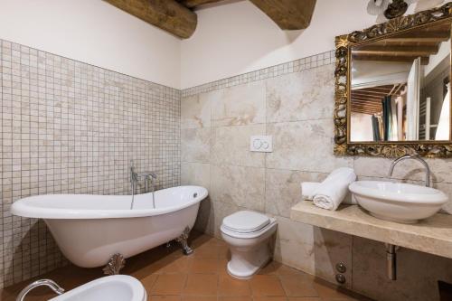 a bathroom with a tub and a toilet and a mirror at Tenuta Tegolato in Barberino di Val dʼElsa