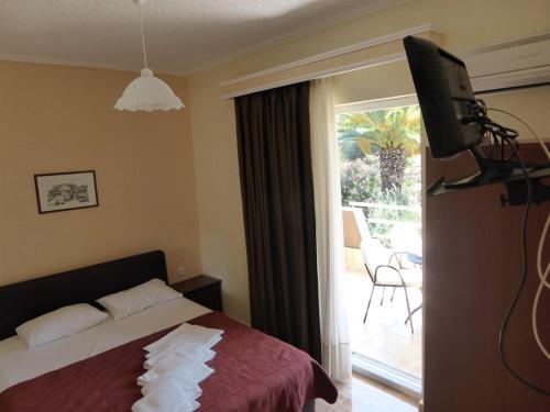 メタモルフォシにあるOlympic Bibis Hotelのベッドルーム(ベッド1台、テレビ、パティオ付)