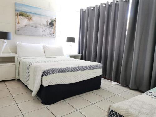 a bedroom with a bed and a window with curtains at Palm Waters Holiday Villas in Townsville