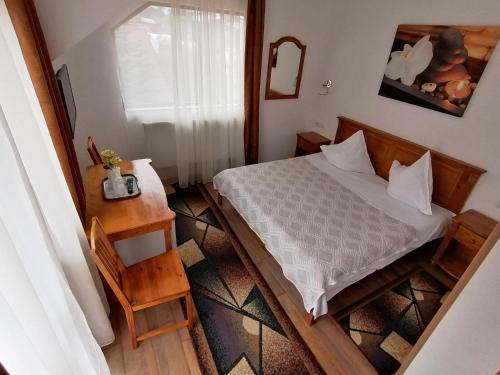 Un pequeño dormitorio con una cama y una mesa. en Casa Magica Busteni, en Buşteni