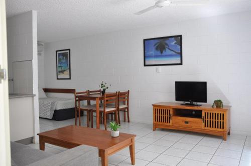 ein Wohnzimmer mit einem TV, einem Tisch und Stühlen in der Unterkunft Palm Waters Holiday Villas in Townsville