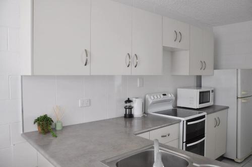eine weiße Küche mit einer Spüle und einer Mikrowelle in der Unterkunft Palm Waters Holiday Villas in Townsville