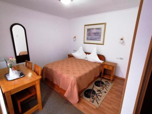 a small bedroom with a bed and a table at Casa Magica Busteni in Buşteni