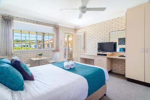 a bedroom with a large bed with two towels at Santa Fe Motel and Holiday Units in Lennox Head