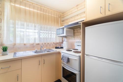 a kitchen with a sink and a white refrigerator at Santa Fe Motel and Holiday Units in Lennox Head