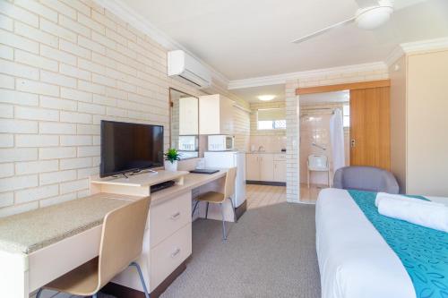 a bedroom with a bed and a desk with a television at Santa Fe Motel and Holiday Units in Lennox Head