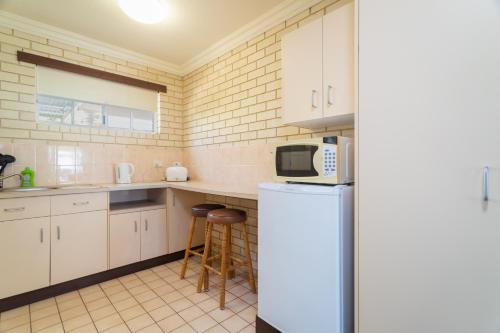 
a kitchen with a microwave, sink, dishwasher and refrigerator at Santa Fe Motel and Holiday Units in Lennox Head

