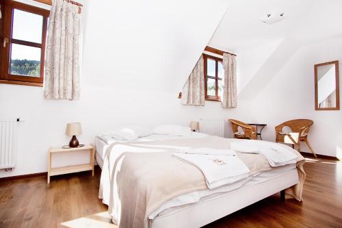 a white bedroom with a bed and two windows at Gorski Potok in Stronie Śląskie