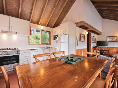 a kitchen and dining room with a wooden table at Banjo 4 Two Bedroom with Loft real fireplace and mountain views in Thredbo