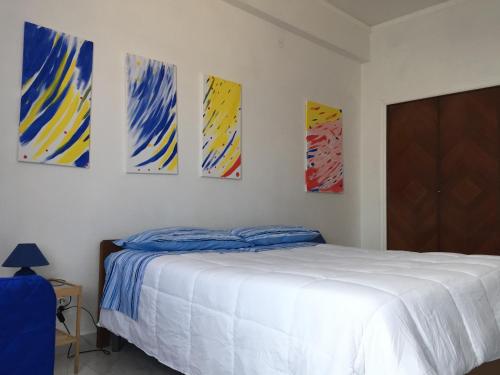 a bedroom with a bed and four paintings on the wall at Atmosfera B&B al centro della città in Cosenza