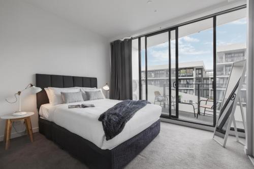 サンドリンガムにあるSandy Hill Apartments by Ready Set Hostのベッドルーム1室(ベッド1台、大きな窓付)