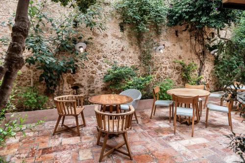 a patio with tables and chairs in front of a wall at Hotel Off in Chania Town